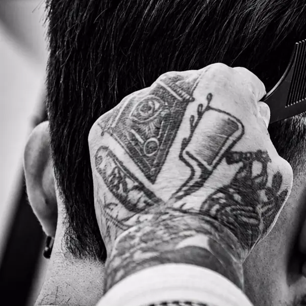 Mano tatuada peinando el corte